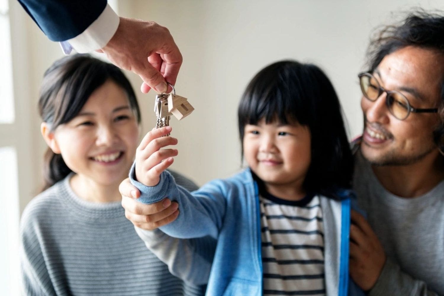 A family is holding keys to their new home.